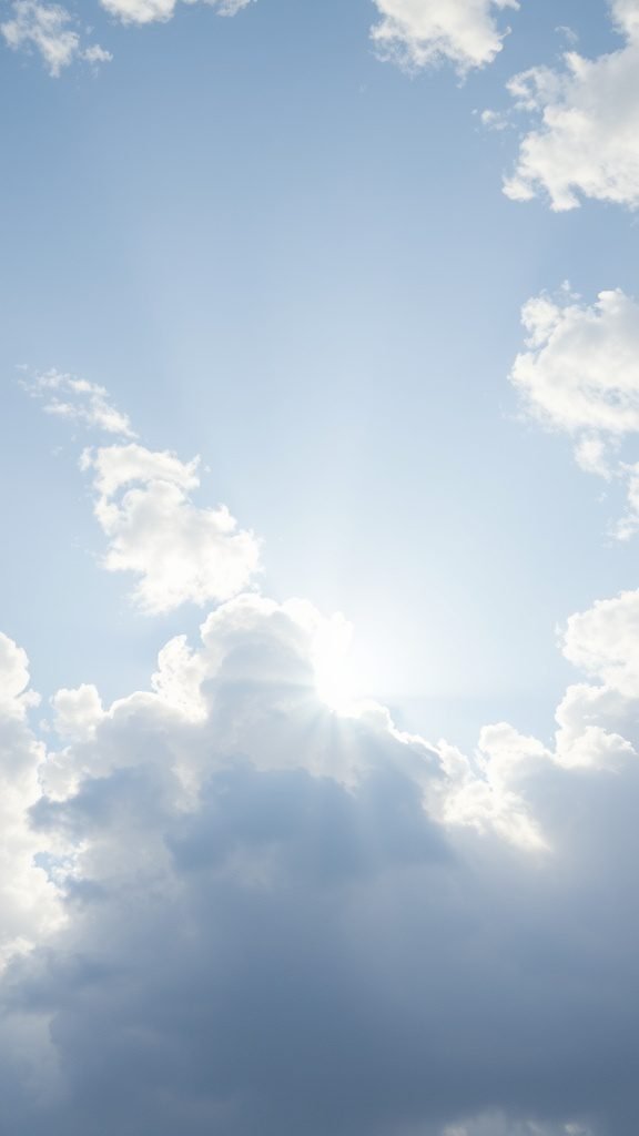 A bright sky with clouds and sunlight shining through, symbolizing the arrival of spring in March.