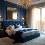Luxurious master bedroom with Prussian blue walls, a navy velvet tufted headboard, and golden hour light through large windows, featuring vintage chandelier, brass sconces, and decor of blue hydrangeas and a gilded mirror.