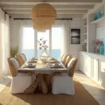 A coastal dining room at golden hour with driftwood table, mixed seating, and ocean views through billowing curtains.