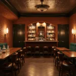 A photorealistic image of a dimly lit basement speakeasy bar with arched brick walls, vintage copper sconces, a pressed tin ceiling, and luxurious emerald velvet banquettes. The walnut bar features a brass footrail and leather-topped barstools, while crystal decanters gleam under warm amber lighting. Backlit glass shelves display premium spirits, with dramatic uplighting and antique mirrors adding to the moody evening ambiance.