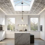 A luxurious modern kitchen with a white PVC coffered ceiling featuring integrated LED lighting, sleek white cabinets, and a marble waterfall island with gold hardware, illuminated by early morning sunlight and ambient LEDs.