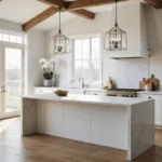 Hyperrealistic architectural photograph of a bright modern farmhouse kitchen featuring white shaker cabinets, a matte Carrara marble waterfall island, rustic oak floors, and sage green accents, illuminated by soft morning sunlight streaming through large windows. The high vaulted ceiling showcases exposed beams and polished nickel hardware, with artistic styling that includes fresh herbs, artisanal cutting boards, and crystal pendant lights, all captured in ultra-high resolution with a cinematic composition.