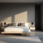 A modern minimalist bedroom with pearl grey walls, a low-profile platform bed, and golden hour sunlight streaming through floor-to-ceiling windows, featuring bleached oak nightstands and geometric grey pillows.