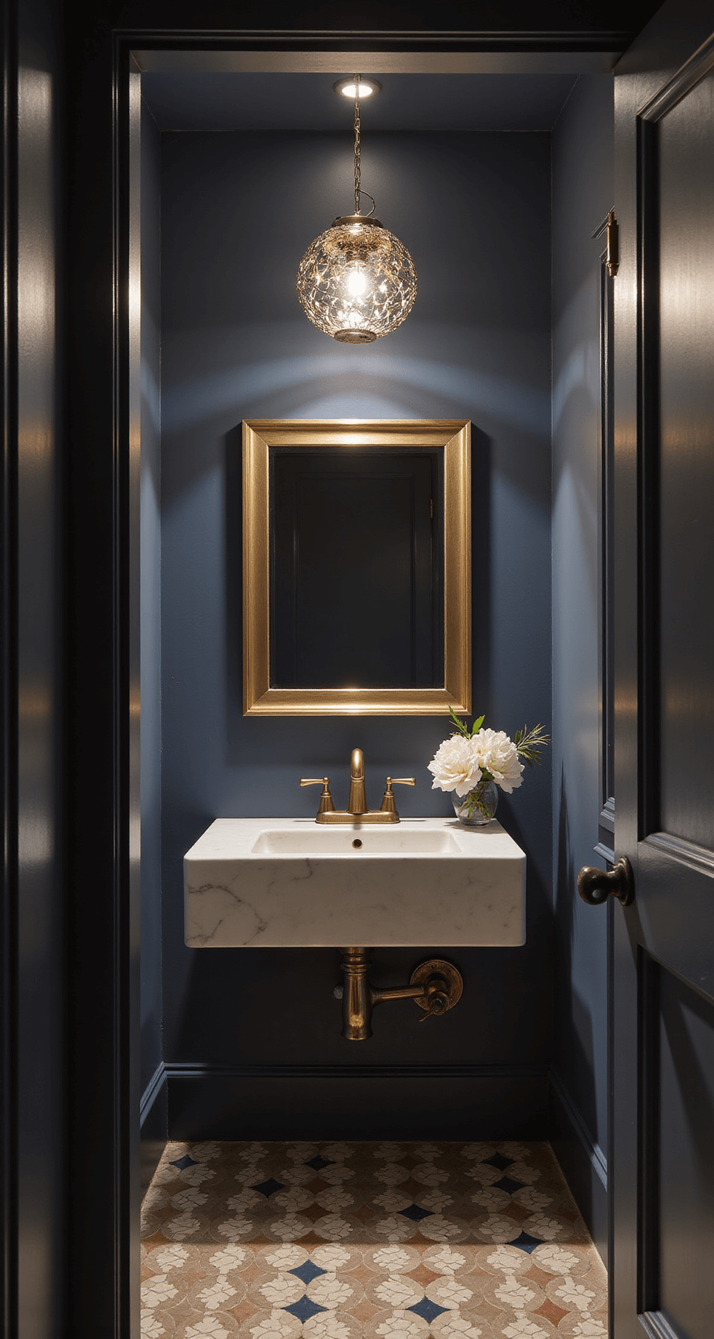 A luxurious powder room with unlacquered brass fixtures against dark navy walls, featuring a handcrafted mixed metal pendant light, brushed bronze vanity hardware, a champagne gold mirror frame, and geometric floor tiles with metallic inlays, all highlighted by focused spot lighting for dramatic shadows.