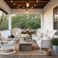 Cinematic wide-angle shot of a cozy modern farmhouse front porch during golden hour, featuring a wraparound wooden deck with white railings, wicker rocking chairs, and seasonal decor including hydrangeas and warm Edison bulb lights.