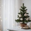 A minimalist Christmas tree on a white marble console, decorated with cream felt ornaments and natural wood slices, featuring a copper accent and warm fairy lights, surrounded by small wrapped gifts and ceramic figurines in soft morning light.